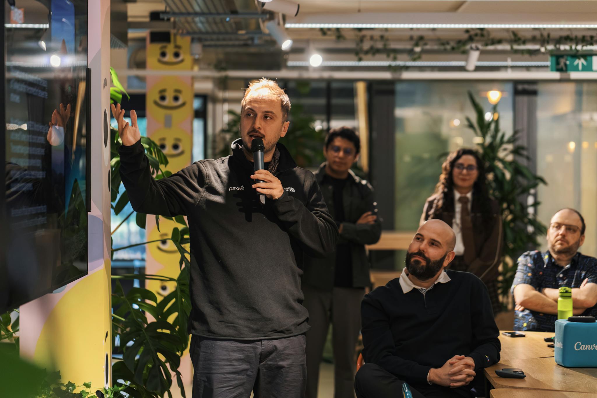 A presenter delivers a business presentation in a modern office environment with attentive audience members.